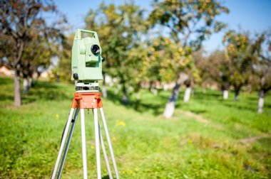 Total station surveying and measuring engineering equipment at work in garden or forest clipart