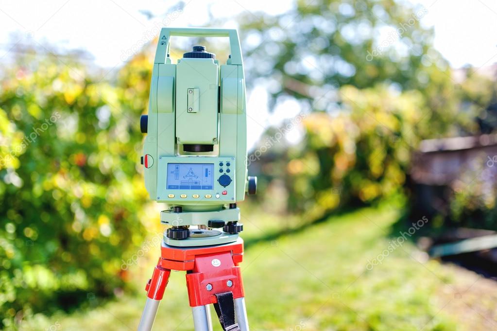 Surveying equipment with transit total station and theodolite with garden background