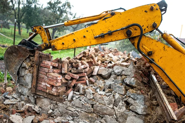 Bulldozer no local de demolição trabalhando em um prédio antigo e carregando tijolos e concreto — Fotografia de Stock
