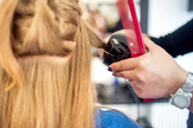 Sarışın kadın ile uzun süreli etkisi bukleler oluşturmak için profesyonel bir araç kullanarak Kuaför Salonu. Güzel kadın farklı stil salon araçlarını kullanma