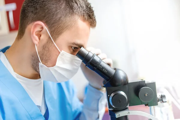 Close-up do homem pesquisador usando um microscópio, exame de amostras em laboratório — Fotografia de Stock