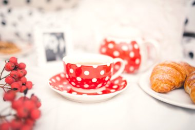 Closeup of red dots coffee cup and croissants as breakfast  clipart