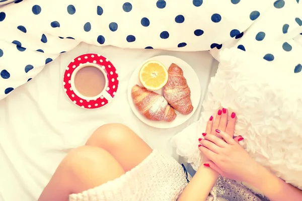 Close-up of woman legs and breakfast in bed with croissant, coffee and orange juice on a lazy sunday morning — Stok Foto