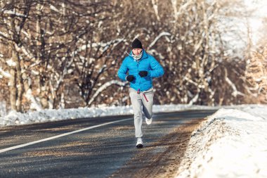 Man fitness concept - running and jogging, outdoor training in snow on a cold sunny day clipart
