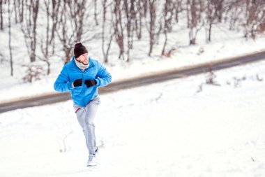 Sağlıklı bir eğitim için kar üzerinde çalışan genç sporcu adam