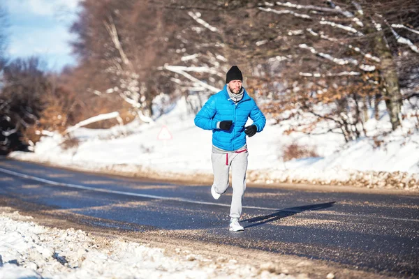 Uomo attivo, jogging e corsa durante una giornata invernale soleggiata. Allenamento all'aperto concetto — Foto Stock