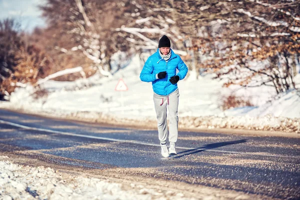 Uomo atletico che fa jogging e si allena all'aperto nel parco con la neve in una giornata fredda — Foto Stock