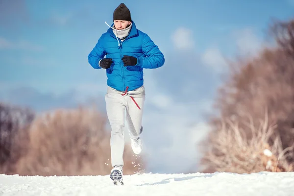 Conceito de aptidão de um homem correndo ao ar livre na neve em um dia frio de inverno — Fotografia de Stock