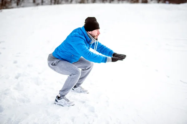 Athletic man doing sit ups on snow, during training and practice. Fitness workout outdoor on a snowy, winter day — Stock Photo, Image