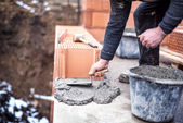 stavební dělník pomocí stěrky a cement pro instalaci zdiva