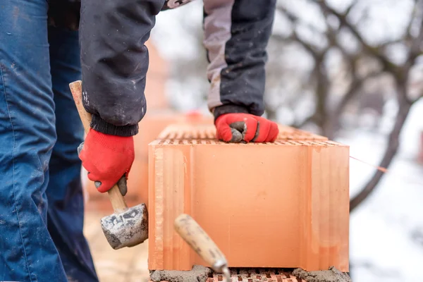 Detalj av arbetare, muraren byggnadsingenjör fastställande tegelstenar och bygga väggar på nytt hus på en kall vinterdag — Stockfoto