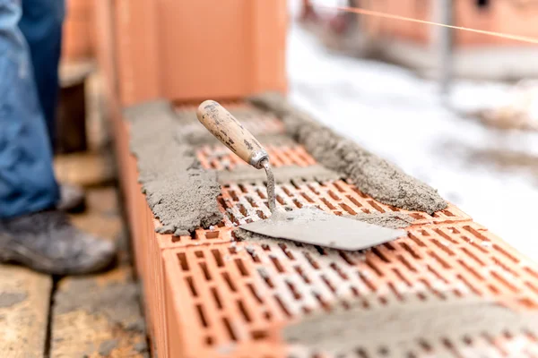 Detalle del sitio de construcción, paleta o cuchillo masilla en la parte superior de la capa de ladrillo — Foto de Stock