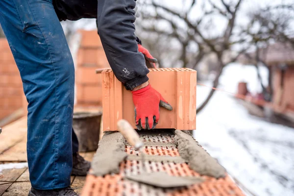 Baustelle und Maurer, der mit Ziegeln, Zement und Mörtel für den Hausneubau arbeitet — Stockfoto