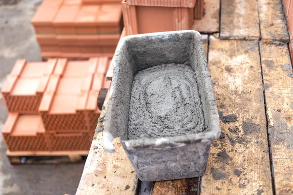 Грязевая сковорода с цементом и раствором для кладки кирпича на строительной площадке — стоковое фото