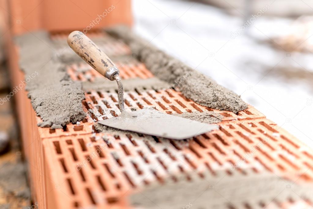 Detail of construction site, trowel or putty knife on top of brick layer