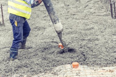 İnşaat işçisi beton döker, pompayı yönetir ve temelde çalışır.