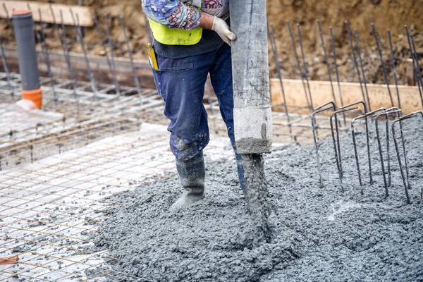 Building construction worker pouring cement or concrete with pump tube — Stock Photo, Image