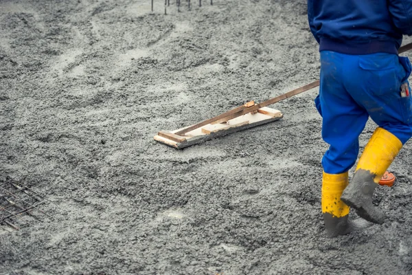 Nivelamento do trabalhador com espátula de madeira o concreto fresco derramado ou cimento no local de construção — Fotografia de Stock