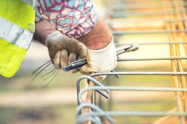 Mãos do trabalhador usando fio de aço e plincers para fixar barras de aço, preparando-se para derramamento de concreto no local de construção — Fotografia de Stock