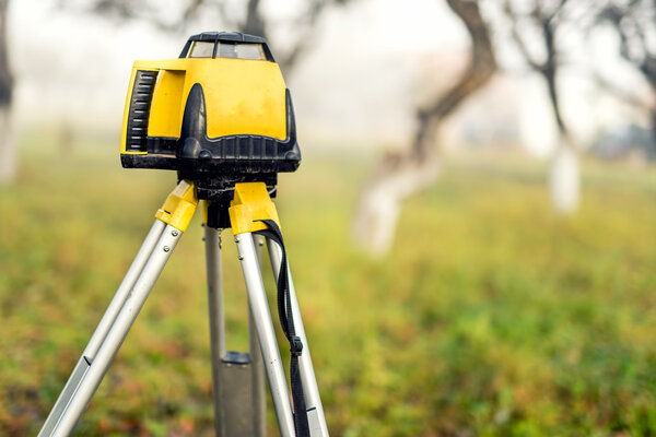 Surveying measuring equipment level theodolite on tripod on a foggy day in construction site