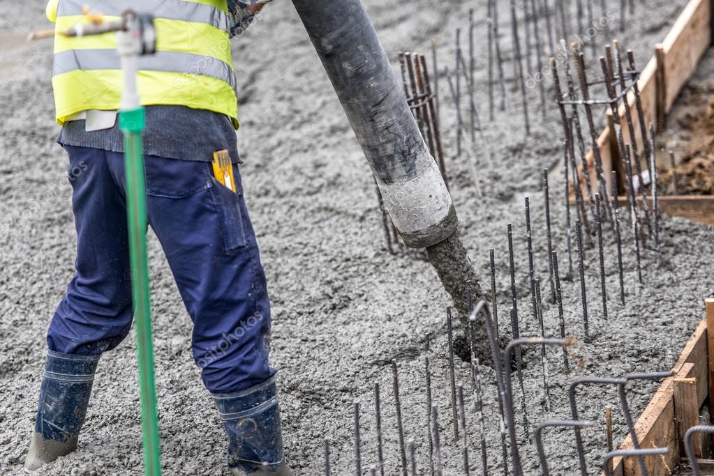 Contruction worker pouring concrete, directing the pump tube — Stock