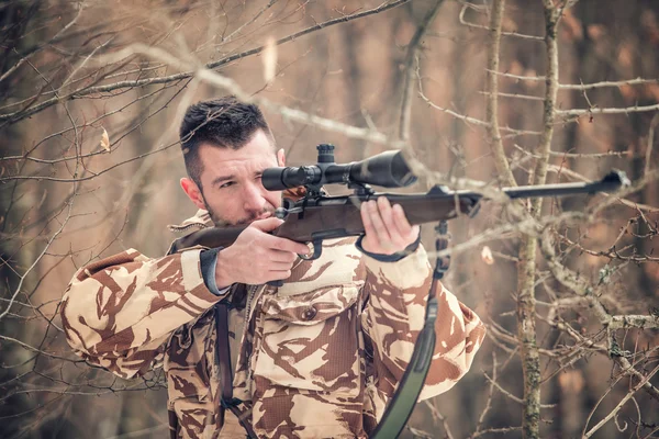 Un homme tenant un sniper et tirant en pleine saison, regardant à travers la lunette — Photo