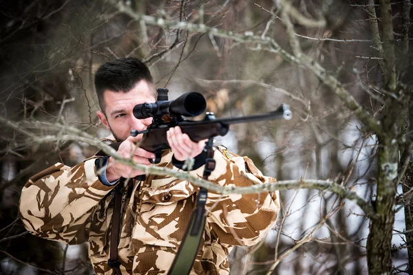 Hunting, army, military concept - sniper holding rifle and aiming at target in the forest during operation — Stock Photo, Image