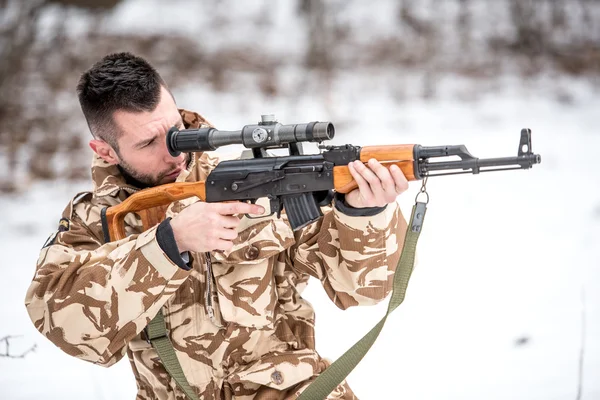 Army katonai trooper holding a fegyvert és a lövés az ellenség a csatatéren — Stock Fotó