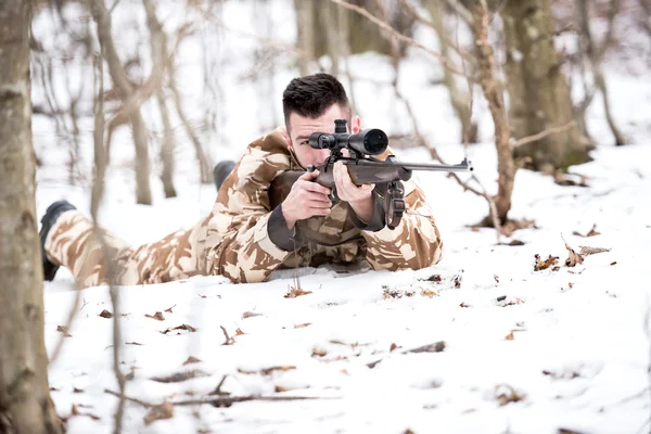 Caçador atirando com um rifle sniper, apontando e disparando balas — Fotografia de Stock