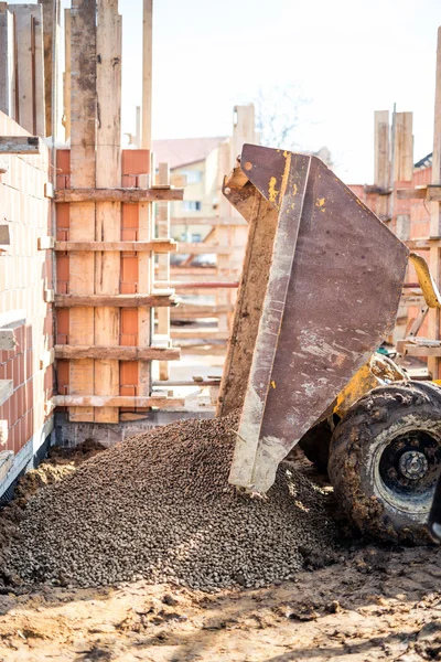 Dumper truck unloading construction gravel, granite and crushed stones at building foundation — Stock Photo, Image