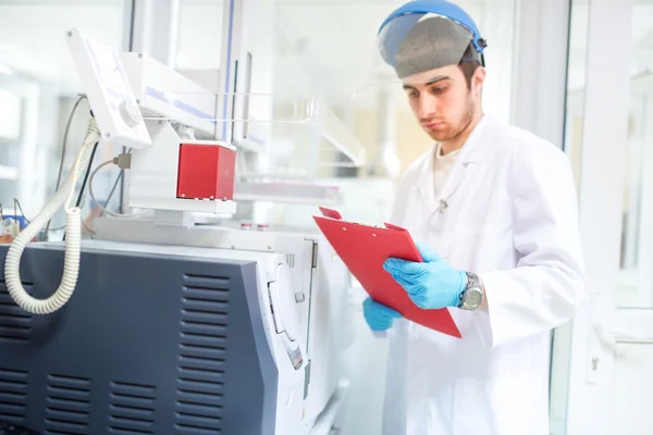 Scientist or doctor using clipboard and reading experiment information from computer — Stock Photo, Image