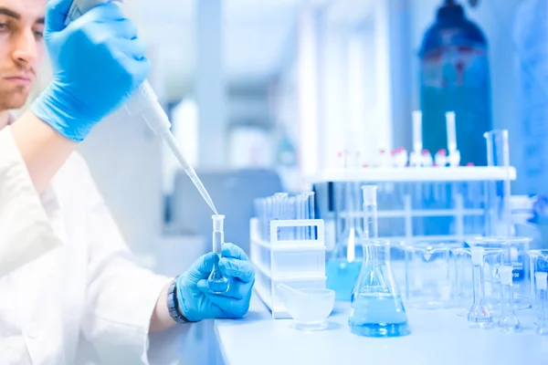 Tubos de ensaio em clínica, farmácia e laboratório de pesquisa médica com cientista masculino usando pipeta — Fotografia de Stock