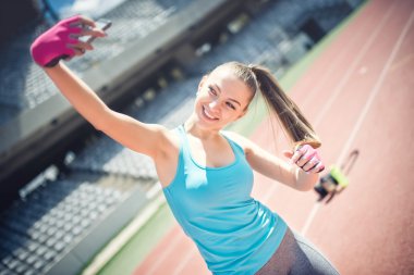 Gülümseyen ve bir selfie ise eğitim alarak güzel bir kız portresi. Güzel bir kadın kendini fotoğrafını çekmek. Sosyal medya, teknoloji ve fitness kavramı