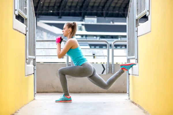 Corridore femminile stretching e fare squat dopo l'allenamento di jogging. Concetto di fitness sullo stadio — Foto Stock