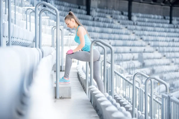 Ženského fitness trenér na schodech, příprava na trénink - protahování a dělat dřepy — Stock fotografie