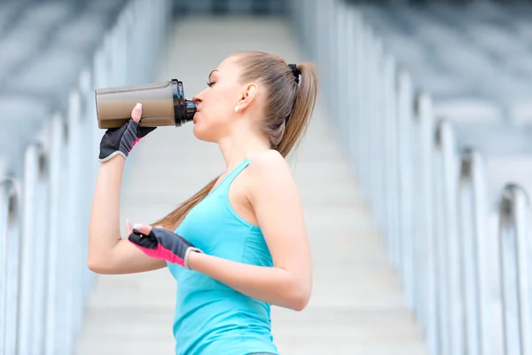 Porträtt av friska fitness tjej dricka proteinshake. Kvinnan dricka sports nutrition dryck medan du arbetar — Stockfoto