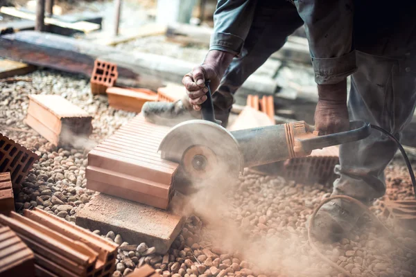 Ouvrier de la construction industrielle utilisant une meuleuse d'angle professionnelle pour couper les briques et construire des murs intérieurs — Photo