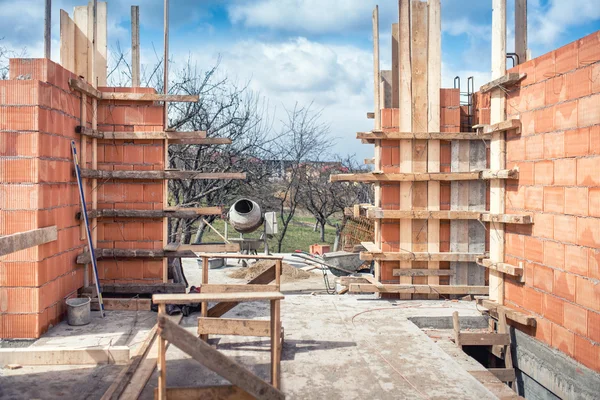 Byggarbetsplatsen, verktyg, skottkärra, sand och tegel vid nya hus byggnad cement mixer maskin och tillbehör — Stockfoto