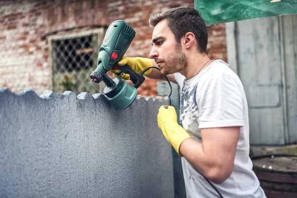 Professionelle Bauarbeiter streichen Wände bei der Renovierung des Hauses. Außensanierung mit Spritzpistolenmaler — Stockfoto