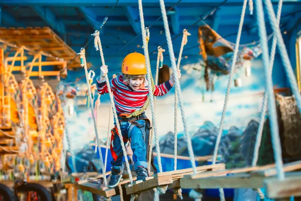 Niño disfrutando de un día de verano y jugando. Niño feliz divirtiéndose en el parque de aventuras, escalando cuerdas y riendo . — Foto de Stock