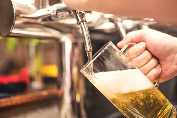 Bistrokellner serviert ein kühles Bier. Hand des Barmanns gießt ein Pils aus dem Zapfhahn — Stockfoto