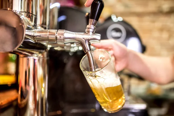 Barmann Hand am Zapfhahn und schenkt ein gezapftes Lagerbier aus, das in einem Restaurant oder Pub ausgeschenkt wird — Stockfoto