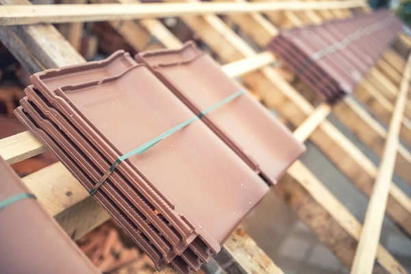 Brown roof tile packs at house construction site. Roof under construction with modern tiles — Stock Image Brown roof tile packs at house construction site. Roof under construction with modern tiles Stock Photo