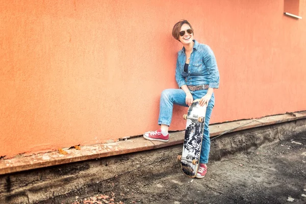 Дівчина з скейтбордом і сонцезахисними окулярами, що живуть у міському стилі життя. Концепція хіпстера з молодою жінкою і скейтбордом, фільтр інстаграм на фото — стокове фото