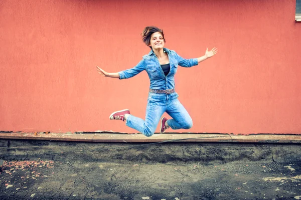 Menina feliz salto e se divertindo. Desportista de jeans e roupa urbana, hipster pulando e sorrindo — Fotografia de Stock