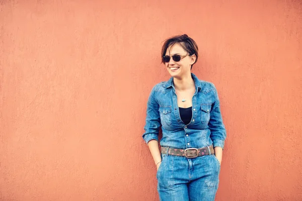 Estilo de vida de moda con hermosa mujer divertida en la terraza con trajes vaqueros modernos, gafas de sol y sonriente. Instagram filtro y efecto suave en la foto —  Fotos de Stock