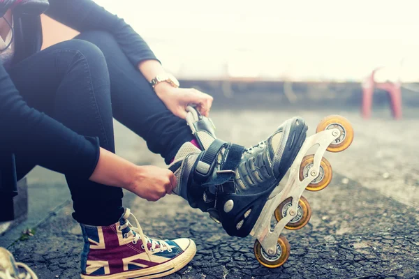 Chica joven feliz disfrutando de patinaje sobre ruedas, patinaje sobre ruedas, poner en patines después de las actividades. Efecto vintage en la foto — Foto de Stock