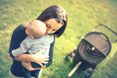 Mother holding her newborn son in hands. Loving mother hand holding cute sleeping newborn baby child in park at sunset