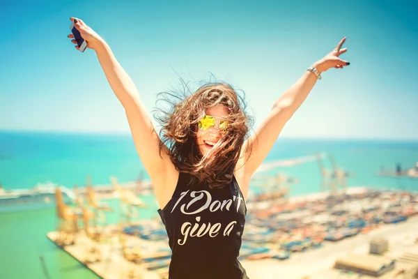 Menina atraente vestindo top tanque preto sorrindo, rindo e tirando fotos com telefone da câmera. Conceito de viagem com mulher feliz. Efeito colorido suave na foto — Fotografia de Stock