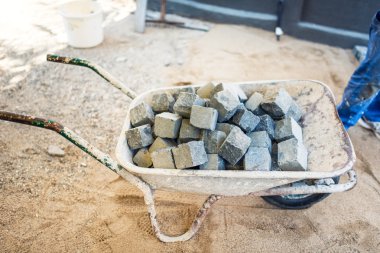 industrial wheelbarrow full of cobblestone, used for pavement on roads, paths and sidewalks. Construction details and tools on building site